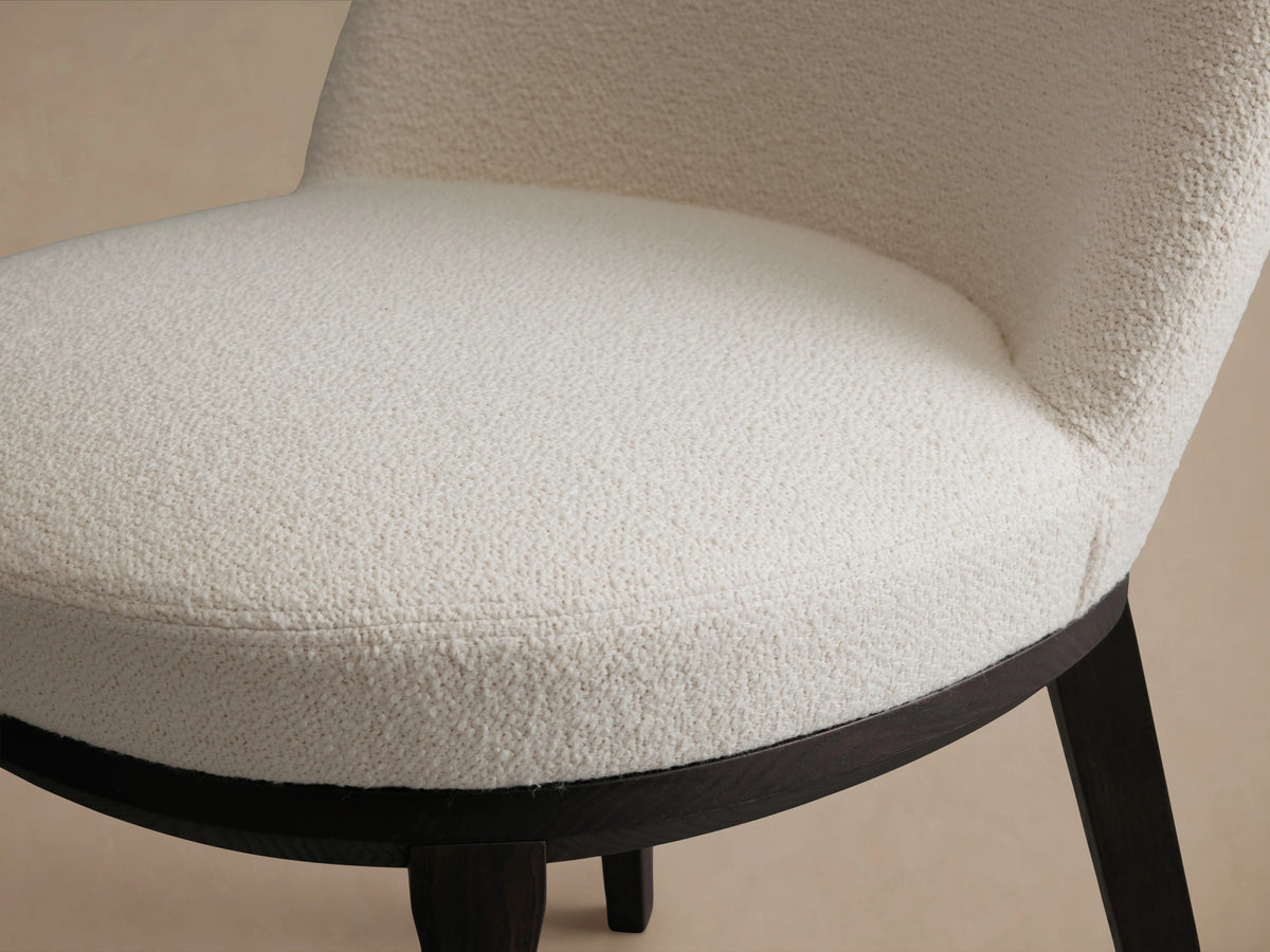 Simone Dining Side Chair with a white upholstered seat and backrest. Features a dark wooden frame on a wooden floor.