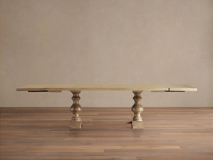 Tuscany Extension Dining Table with a light wood finish, two pedestal legs, and extended leaves on both ends against a neutral background.