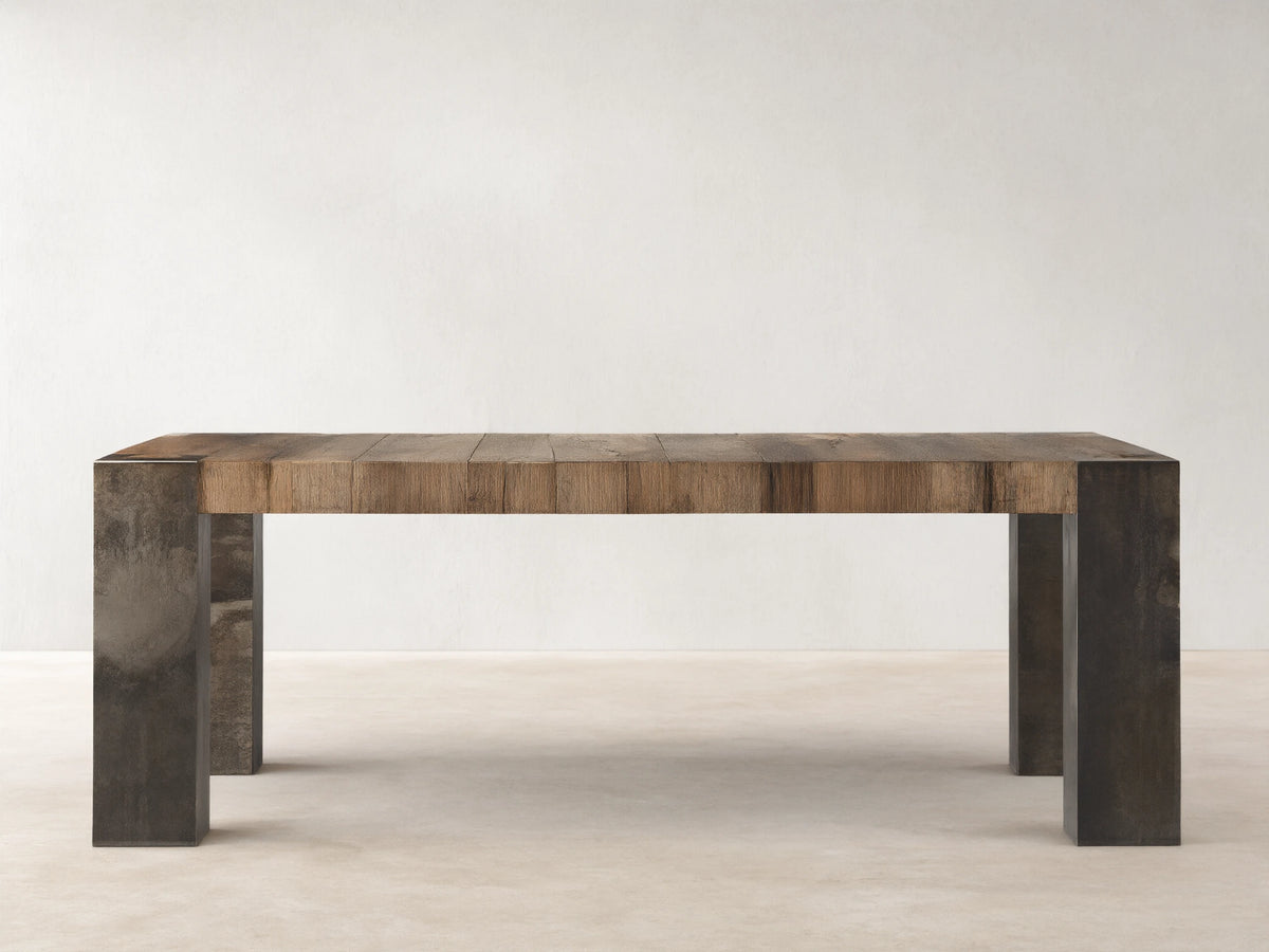 Rectangular Telluride dining table featuring a solid oak wood top with natural variations; oxidized steel legs with distressed patina.