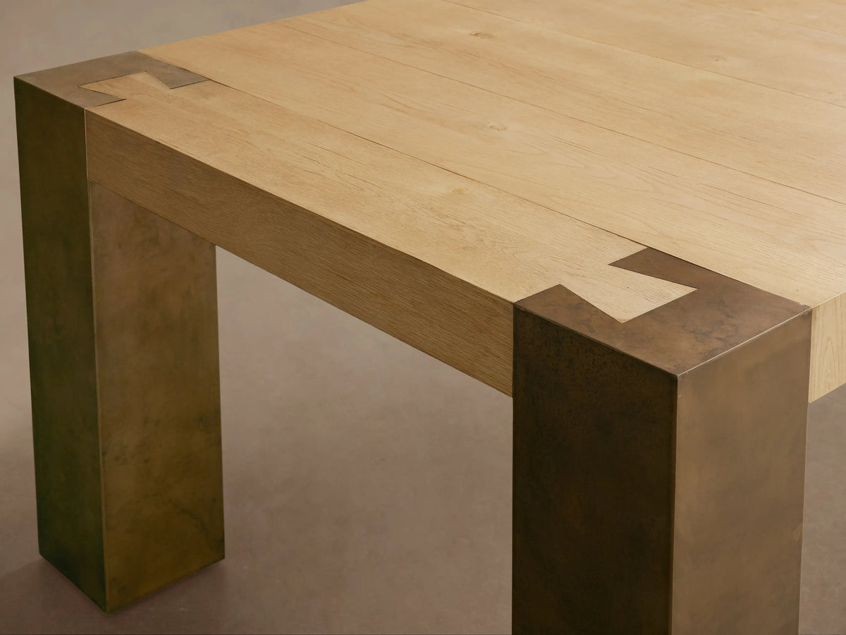 Telluride Dining Table with light oak tabletop, dark oxidized steel legs & corner accents, on a wood floor.