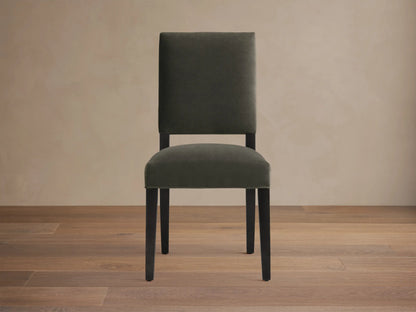 Torino Dining Chair with dark fabric upholstery, solid tapered maple legs on wooden floor, against a neutral wall.