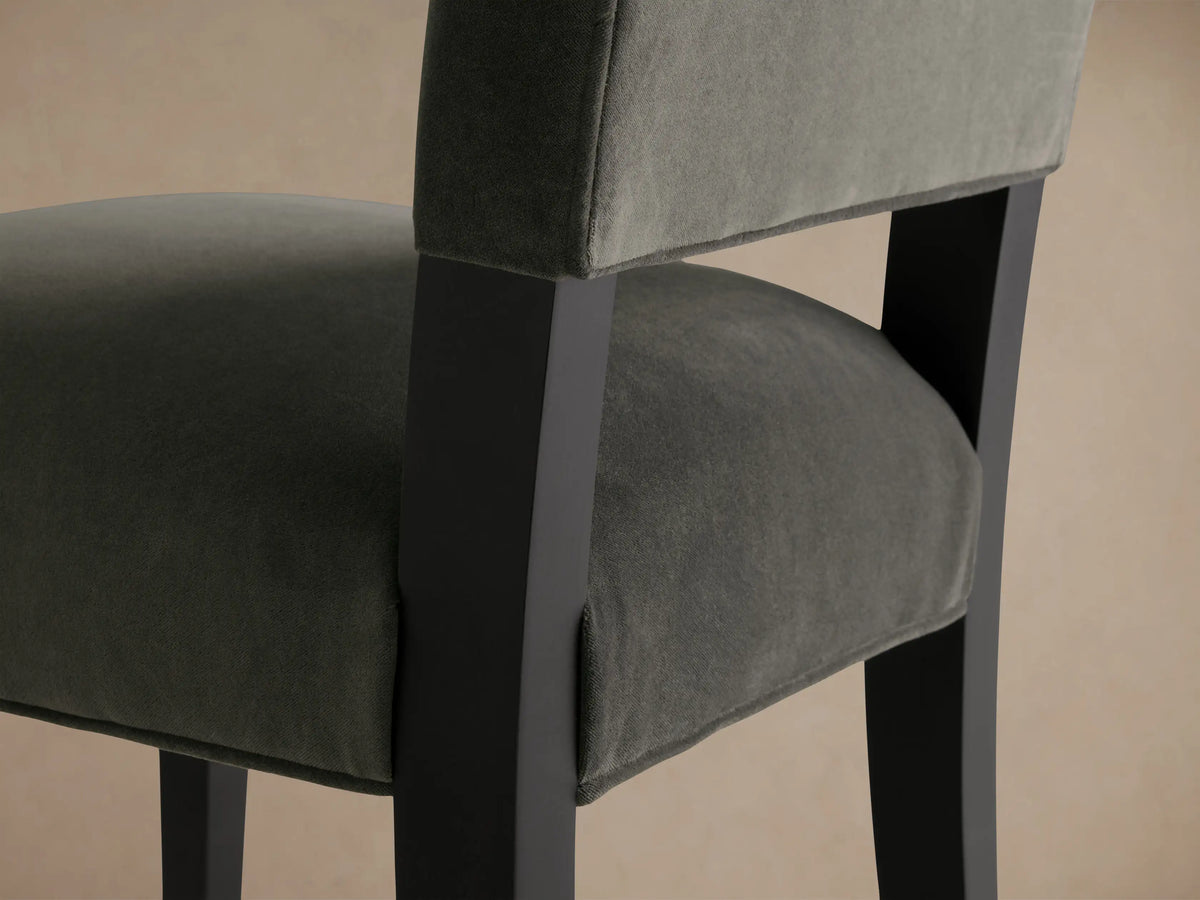 Torino Dining Chair with a dark upholstered seat and backrest, solid tapered maple legs, set against a wooden floor and neutral wall.