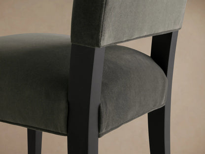 Torino Dining Chair with a dark upholstered seat and backrest, solid tapered maple legs, set against a wooden floor and neutral wall.
