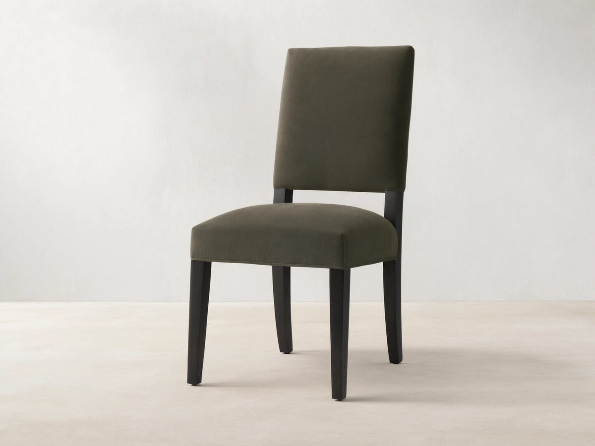 Torino Dining Chair with dark fabric upholstery, solid tapered maple legs on wooden floor, against a neutral wall.