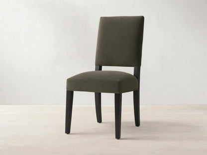 Torino Dining Chair with dark fabric upholstery, solid tapered maple legs on wooden floor, against a neutral wall.