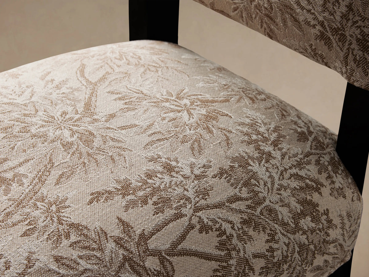 Torino Dining Chair with floral-patterned upholstery in beige and brown, featuring a high backrest. Black tapered wooden legs on a wooden floor.
