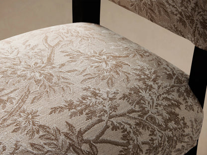 Torino Dining Chair with floral-patterned upholstery in beige and brown, featuring a high backrest. Black tapered wooden legs on a wooden floor.