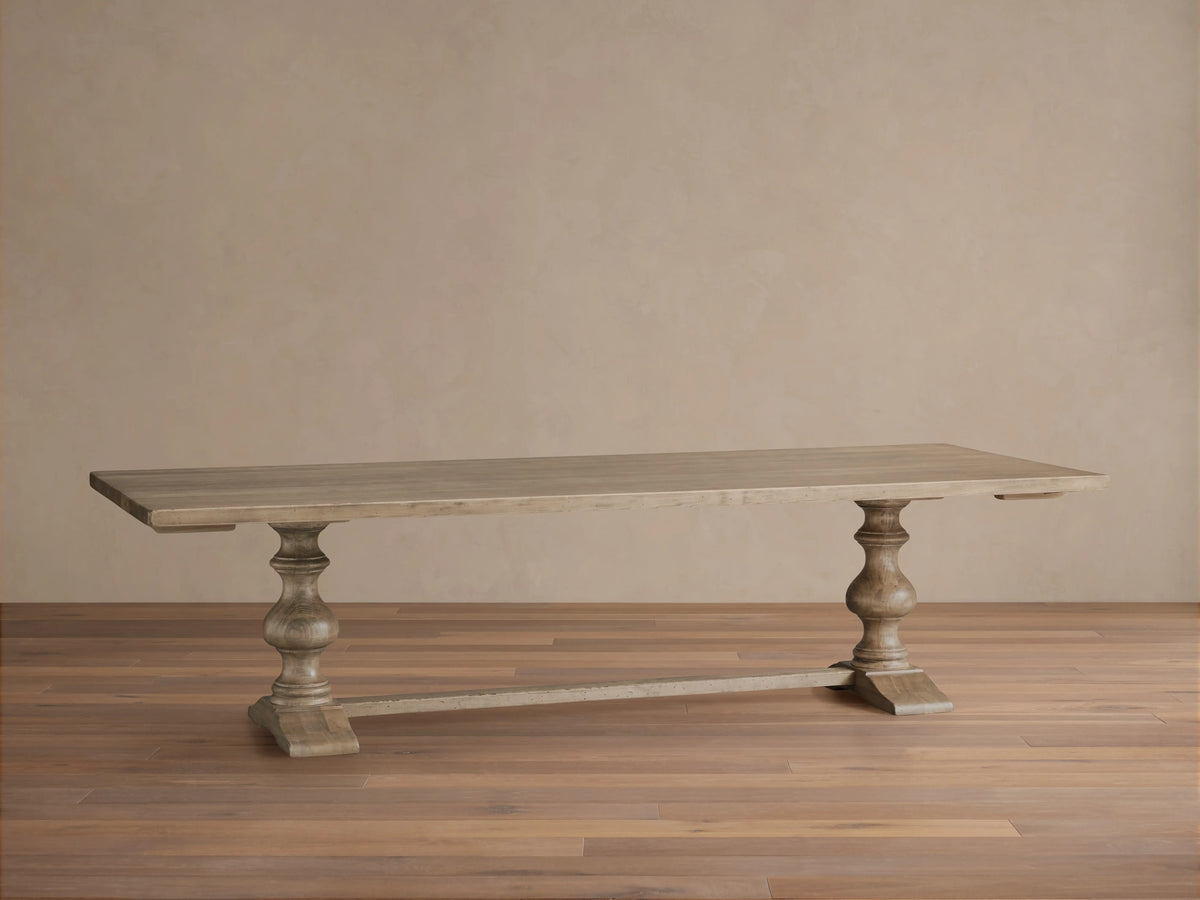 Tuscany Oval Extension Dining Table with a warm, rustic finish, hand-turned pedestal legs, and horizontal trestle on wooden floor.