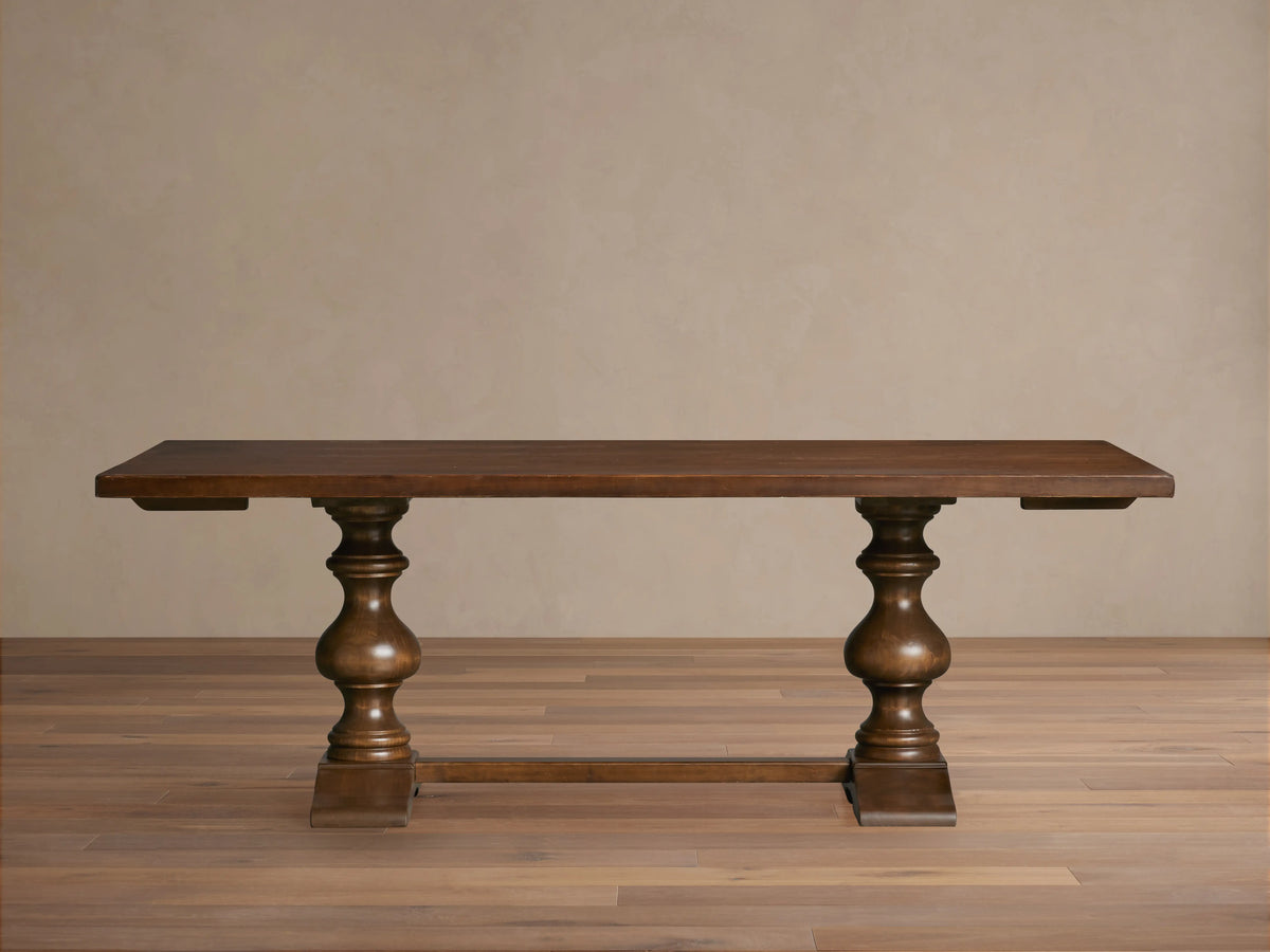 Tuscany Oval Extension Dining Table in dark wood, with an oval shape and hand-turned pedestal legs on a wooden floor.