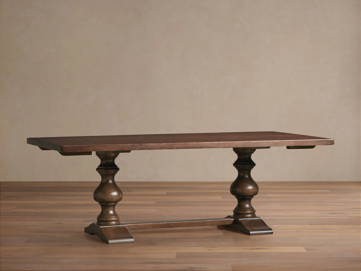 Tuscany Oval Extension Dining Table with rich brown finish, hand-turned pedestal legs and horizontal trestle on a wooden floor.