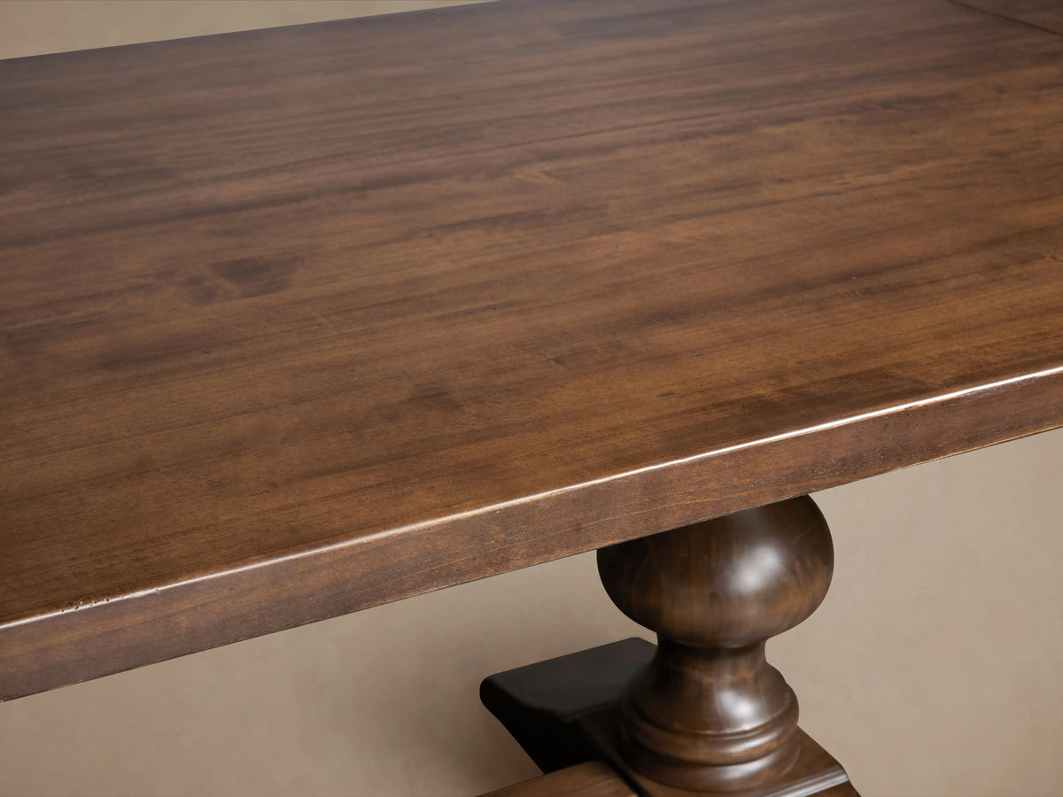 Tuscany Oval Extension Dining Table with a rich brown finish, featuring a rectangular top and ornate pedestal legs connected by a trestle.