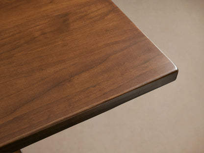 Tuscany Extension Dining Table with a rich brown finish, hand-turned pedestal legs, and horizontal trestle, sits in a room.