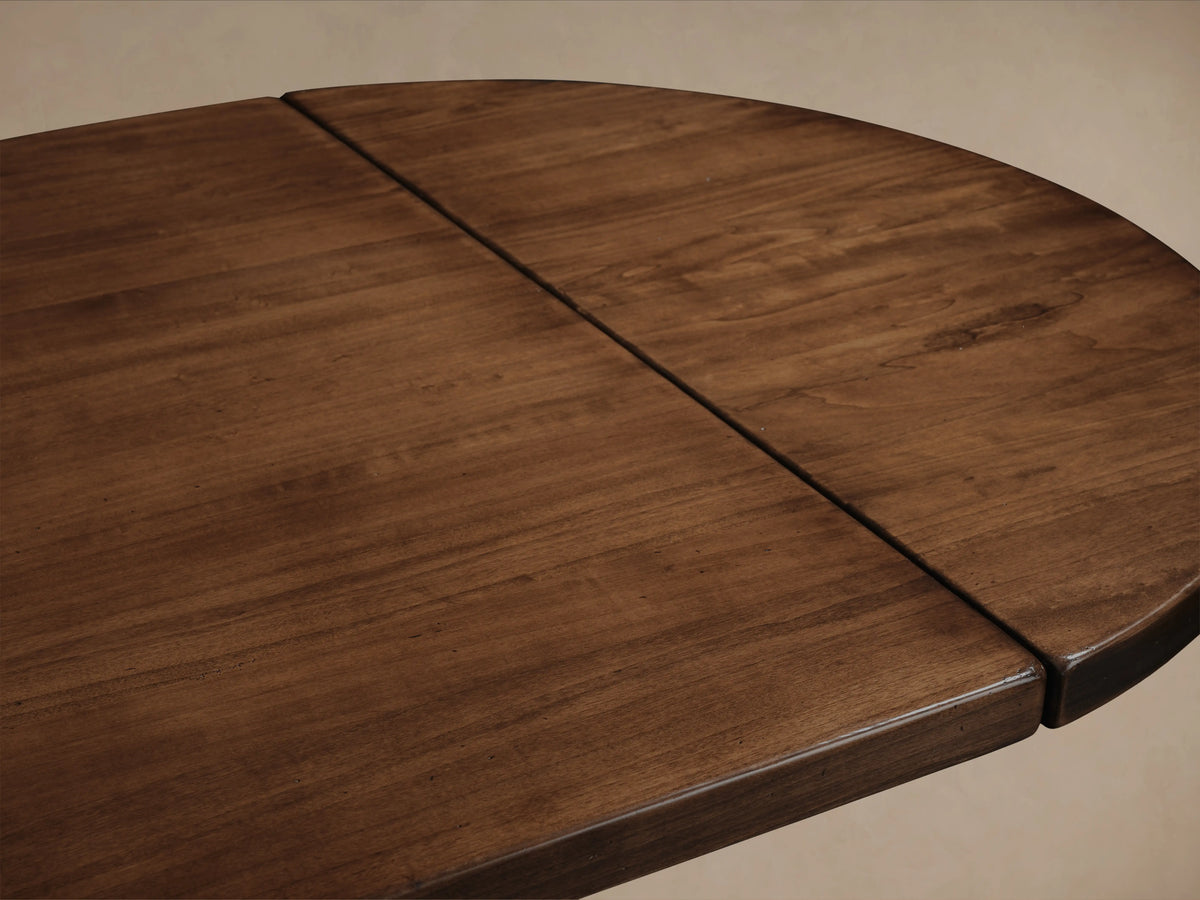 Tuscany Oval Extension Dining Table in warm poplar wood finish, showing smooth tabletop with hand-turned pedestal legs and subtle grain texture.