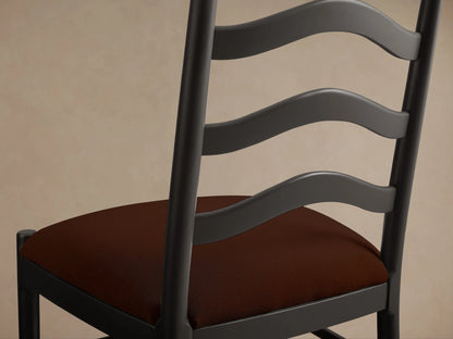 ¾ view of the Vivianna Dining Side Chair with a dark frame, wavy ladder-back, and a reddish-brown padded seat.