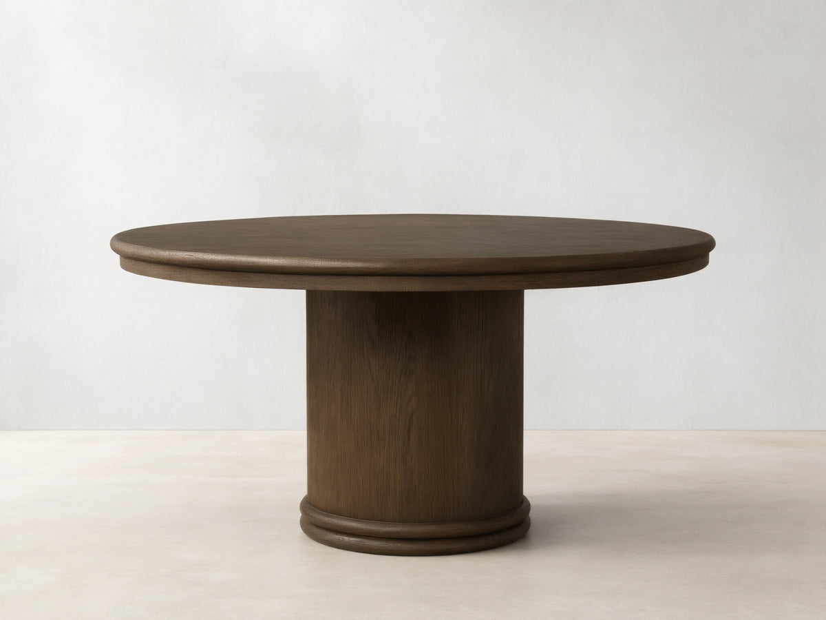 Front view of a mocha-toned Warby Round Dining Table, featuring a smooth round top and a thick cylindrical pedestal base.