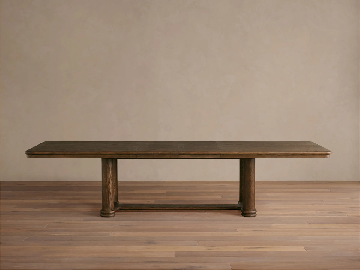 Close-up view of the substantial mocha Warby Extension Dining Table, crafted from solid oak wood, with decorative items on top.