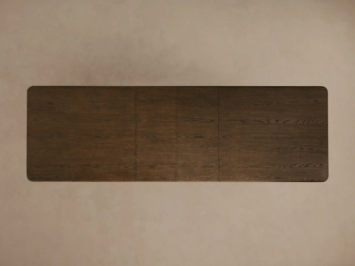 Dark wood Warby Extension Dining Table with large round legs and a smooth, textured finish on a neutral surface.