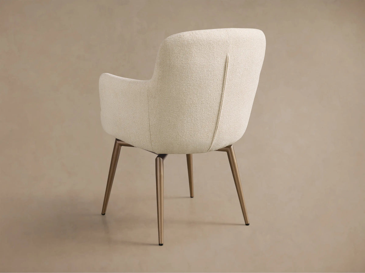Close-up of the cream Willem Dining Arm Chair, showing the curved armrest and textured boucle fabric on the back.