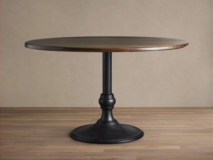 Round dining table with a dark walnut tabletop and a sturdy black cast iron base with a brass finish. Placed on a wooden floor.