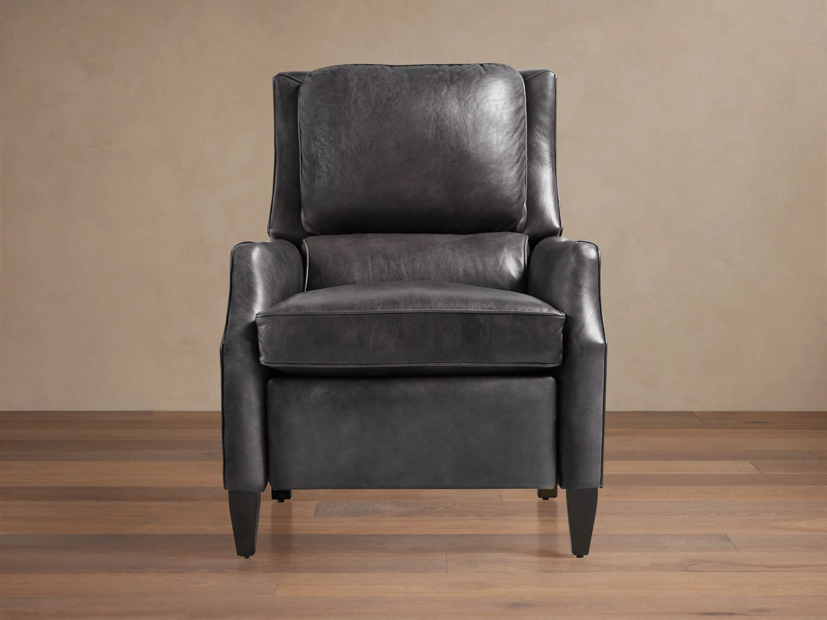 Alex Leather Recliner, dark gray, angled front-right. Features wingback design, contrast piping, tapered dark wood legs, on wood floor.