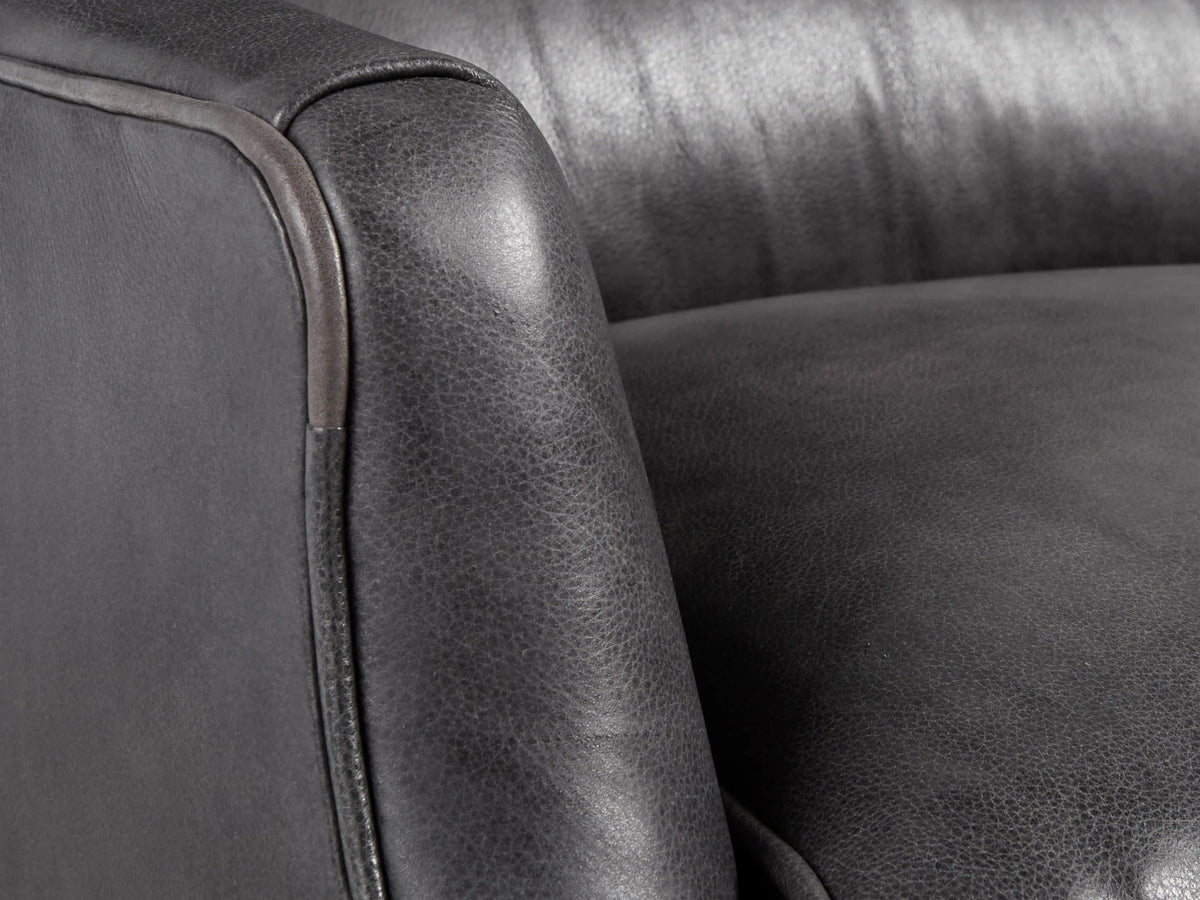 Dark gray Alex Leather Recliner, front view, with cushioned back, lumbar pillow, and tapered dark legs on a wooden floor.