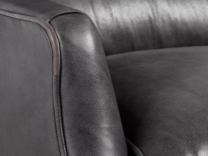 Dark gray Alex Leather Recliner, front view, with cushioned back, lumbar pillow, and tapered dark legs on a wooden floor.