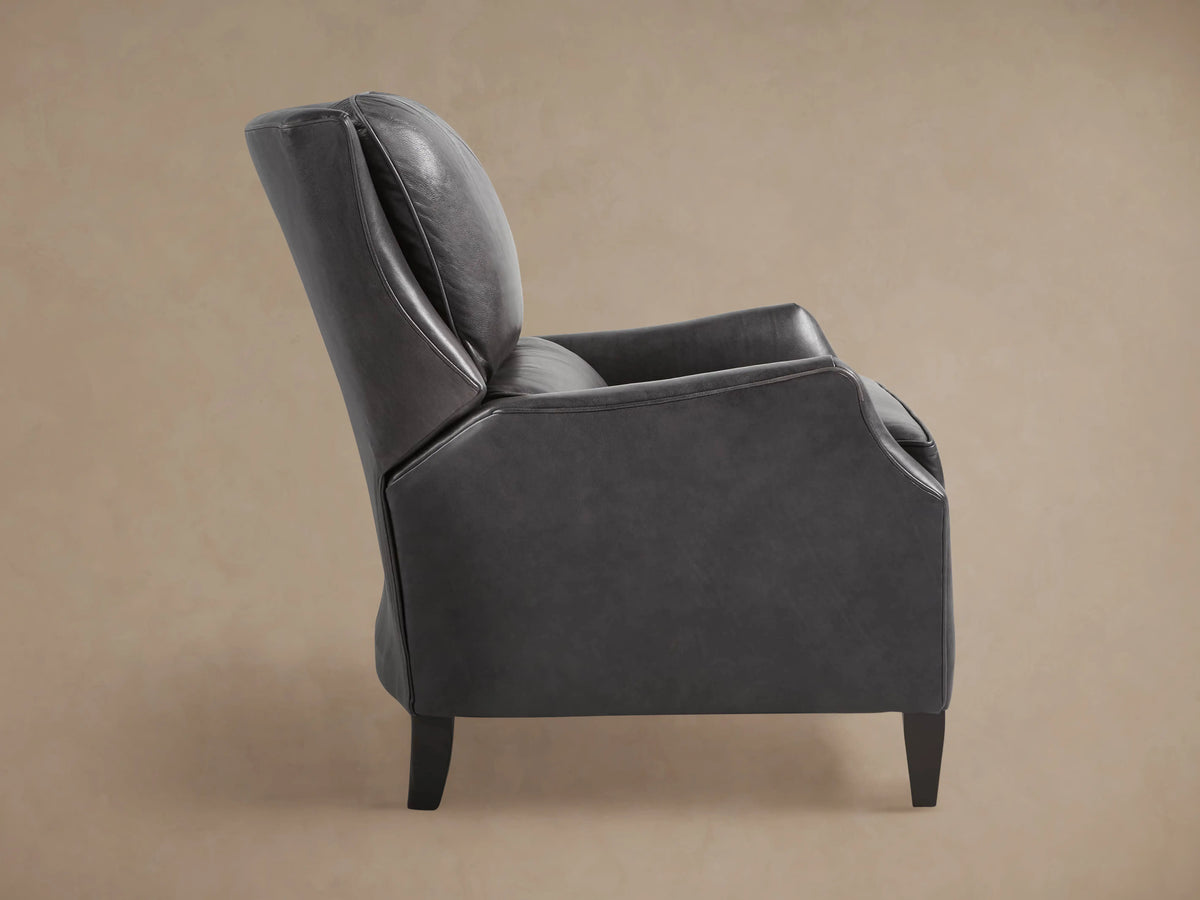 Angled back view of Alex Leather Recliner in charcoal leather with high back, detailed stitching, and dark tapered legs.