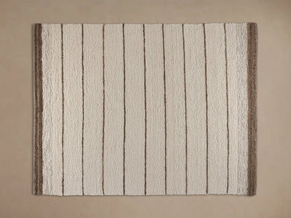 Alice Performance Rug: textured cream-colored rug with horizontal tan stripes and a thick dark brown border, on a wood floor.