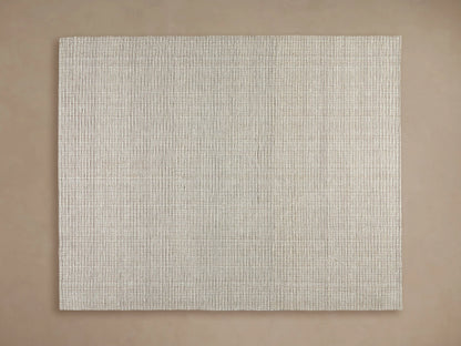 Dover Performance Rug in light beige with horizontal textured lines, partially beneath a wooden coffee table on a wood floor.