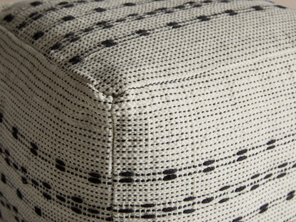 Ladera Performance Pouf corner in beige with black dotted and dashed patterns, showing textured polyester fabric.