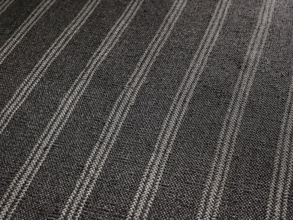 Grover Performance Rug: square, charcoal with thin white vertical stripes, laid flat on a light brown textured surface.