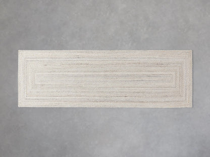 Sansa Performance Runner Rug, light rectangular braided rug with subtle inner rectangular border, on a gray floor.