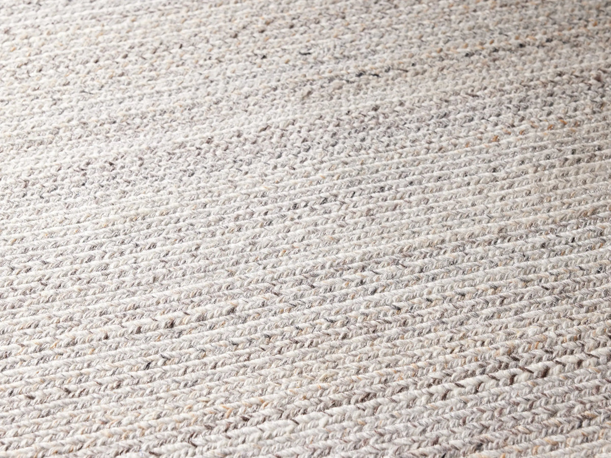 Sansa Performance Runner Rug, light rectangular braided rug with subtle inner rectangular border, on a gray floor.