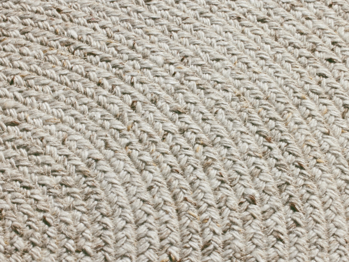 Sansa Performance Round Rug, light cream/off-white, woven in concentric circles, laid flat on a warm beige background.