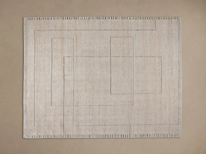 Close-up of a light beige Walker Performance Rug with raised linear and geometric patterns, partially under a wooden table on a wood floor.