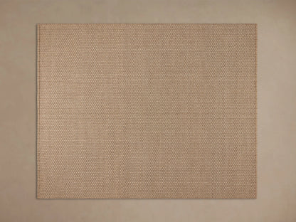 Hatcher Performance Rug with dense beige & brown weave, on a dark wood floor, partially under a light wood coffee table.