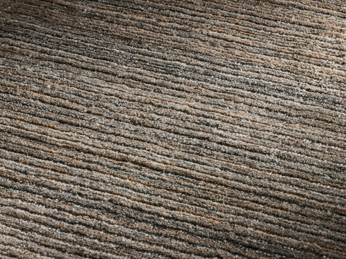 Front view of a round rug with a striated pattern in shades of brown and gray.