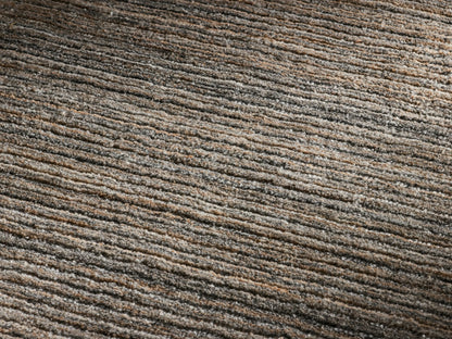 Front view of a round rug with a striated pattern in shades of brown and gray.