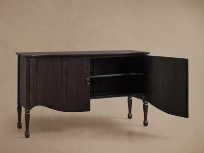 Dark brown Conrad Sideboard, front view, with fluted doors, brass knobs, curved base, and turned legs.