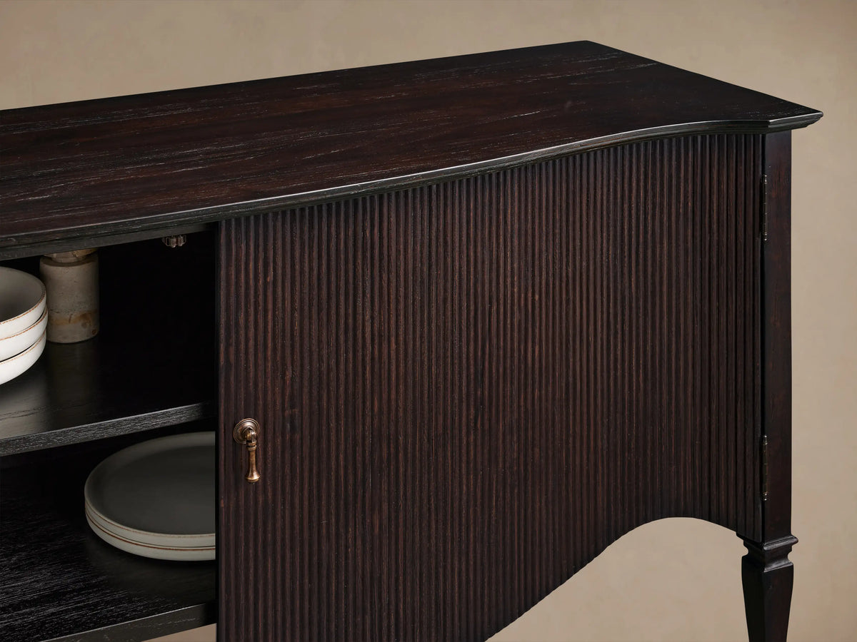 Dark Dhurrie Brown Conrad Sideboard with one ribbed door closed, one door open showing a shelf, and turned legs.