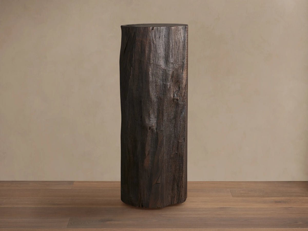 Closed Log Bar, upright, dark brown reclaimed wood, textured like a natural log, on a brown wooden floor against a beige wall.