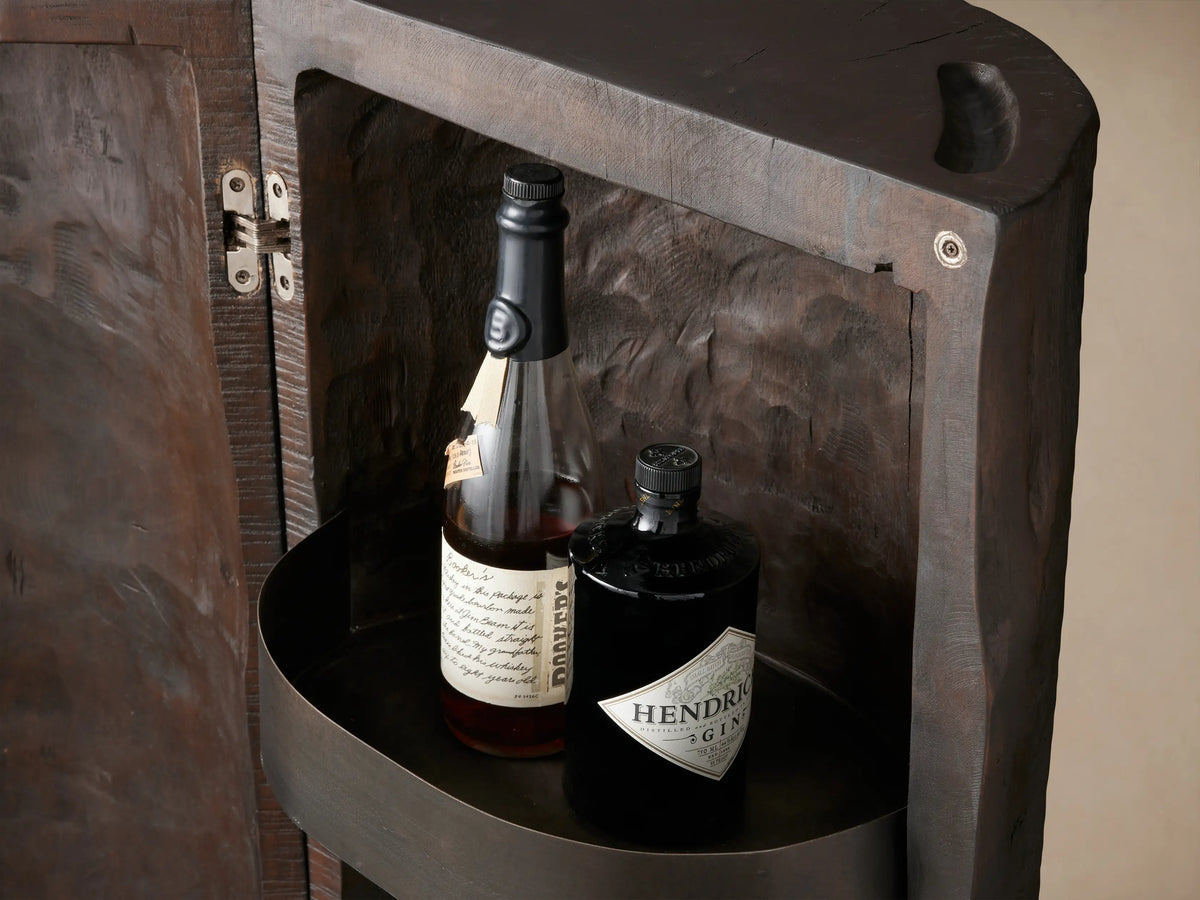 Open Log Bar made from dark reclaimed wood, showing 3 metal shelves filled with bottles & glasses against a brown wall.