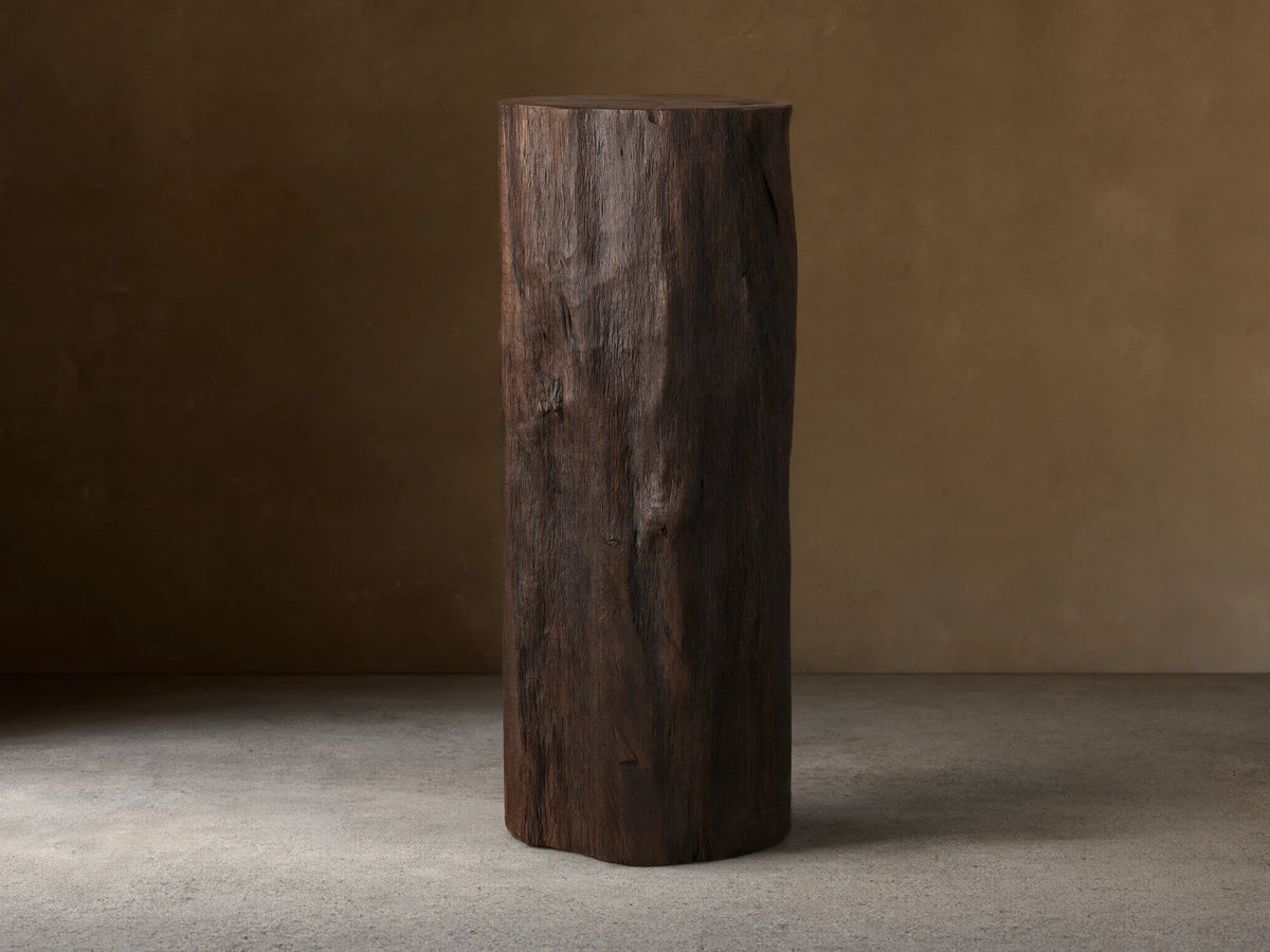 Closed Log Bar, upright, dark brown reclaimed wood, textured like a natural log, on a brown wooden floor against a beige wall.