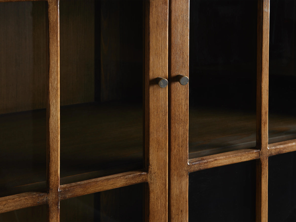 Close-up of Merritt Cabinet showing hand-painted distressed wood with subtly antiqued brass knobs. Visible glass paneled doors.