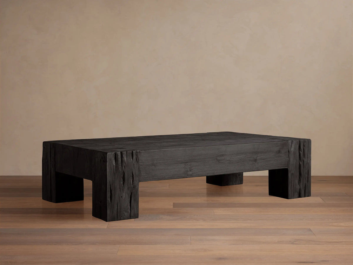 Ubud Coffee Table: Low rectangular table made of dark, textured reclaimed teak wood with a Shou Sugi Ban finish on a wooden floor.