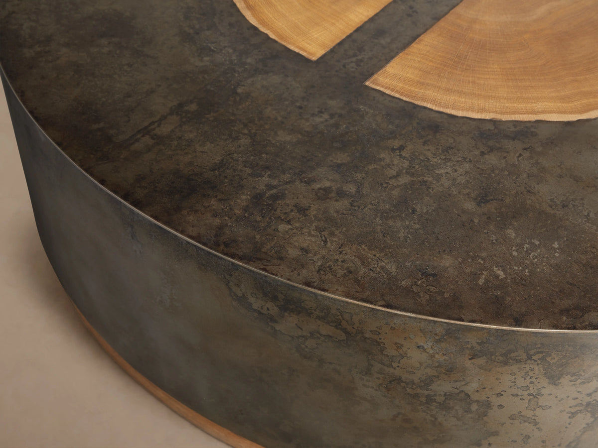 Round coffee table with a naturally oxidized steel base and reclaimed yukas tree veneer top. Weathered finish, unique textures.