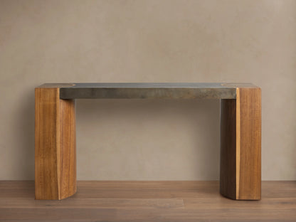 Acacius Console Table with oxidized steel top and thick legs made from reclaimed yukas wood, against a beige wall.