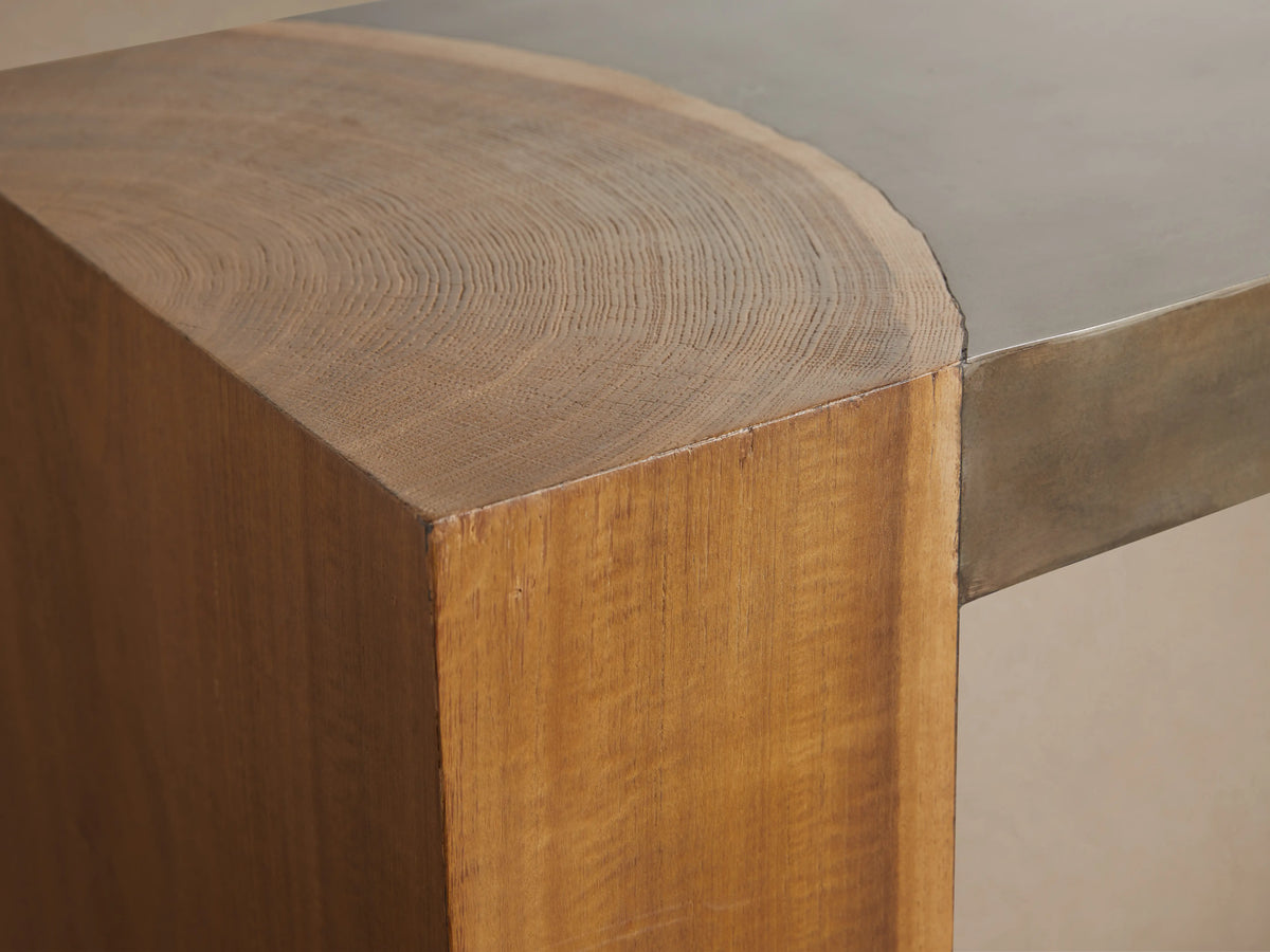 Acacius Console Table with oxidized steel top and thick legs made from reclaimed yukas wood, against a beige wall.