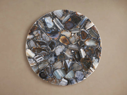 Ludlow Martini Table with a round tabletop featuring a mosaic of polished stones in varying natural tones, set against a neutral background.