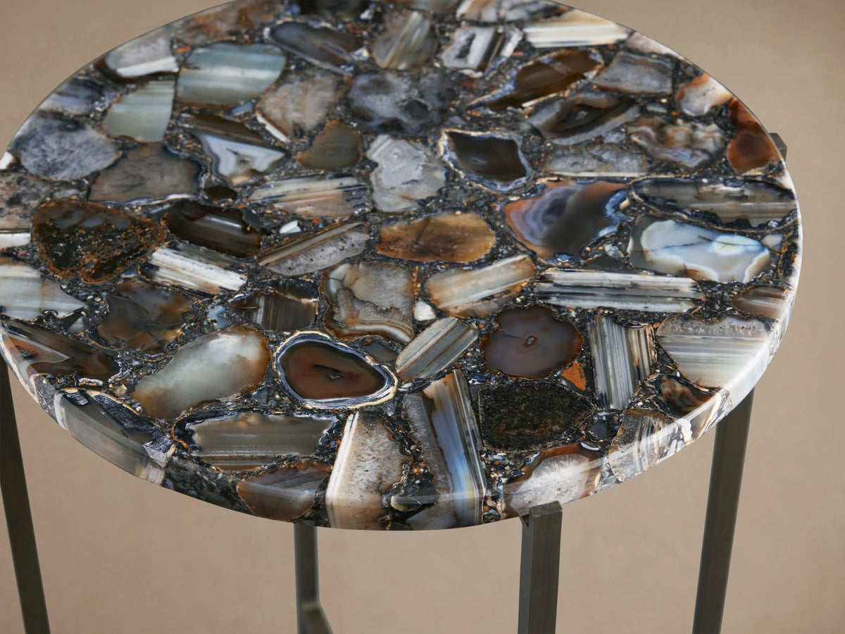 Ludlow Martini Table with a circular tabletop featuring polished stones in varied brown and gray hues atop an iron base.